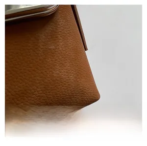 Macro detail of caramel lychee grain leather texture on minimalist shoulder shell bag