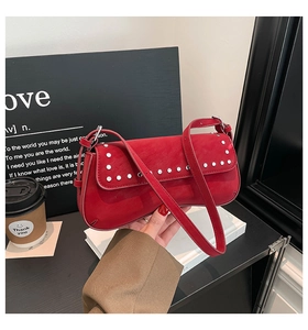 Detail shot of the red leather underarm bag with silver rivet studs and fine texture