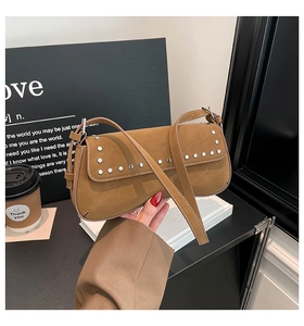 Detail of caramel brown rivet shoulder bag held against urban lifestyle background decor