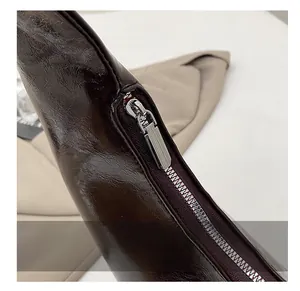 Détail de la fermeture éclair argentée et de la texture du cuir verni sur le sac