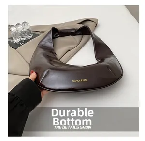 Détails du sac demi-lune marron brillant montrant la texture et la base robuste