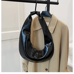 Détail du sac croissant noir brillant avec fermeture éclair argentée et anse intégrée