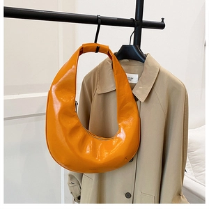 Détail du sac croissant orange brillant avec fermeture éclair en métal sur cuir verni