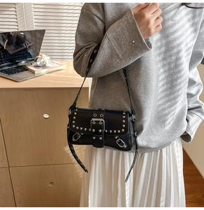 Detailed view of black rivet shoulder bag with silver studs on leather strap and flap