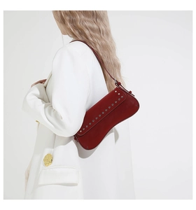 Detail view of burgundy leather hobo bag with silver studs on white blazer outfit