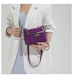 Detail of purple suede crossbody bag featuring vintage metal frame and clasp closure