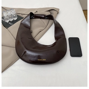 Détail du sac bandoulière marron glacé en forme de croissant avec logo doré