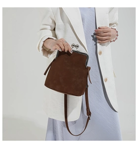 Detail of dark brown vintage clasp square bag with metal spheres on model's shoulder