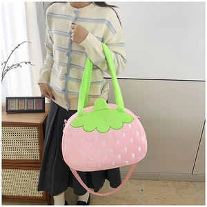 Vue détaillée d'un sac fraise en peluche avec anse verte porté par un mannequin
