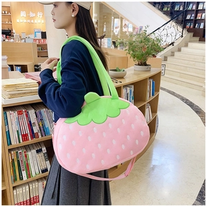 Détail du sac fraise en peluche rose avec broderies blanches et feuilles vertes