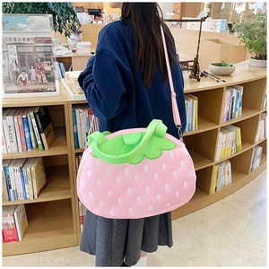 Détail du sac fraise en peluche avec feuilles vertes et bandoulière en toile rose
