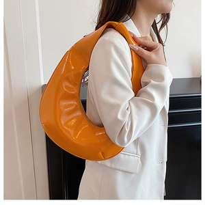 Détail du sac hobo orange brillant avec fermeture éclair argentée sur costume blanc
