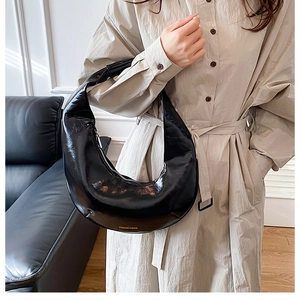 Détail du sac demi-lune en cuir verni noir avec inscription dorée élégante en gros plan
