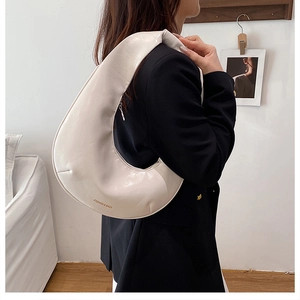 Détail du sac demi-lune crème montrant l'imprimé FASHION & BAGS sur le panneau latéral