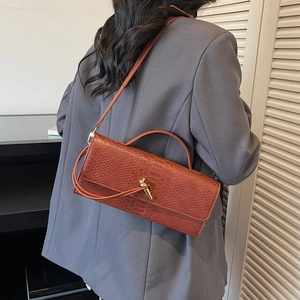 Brown faux snakeskin crossbody bag with gold buckle detail shown on a female model