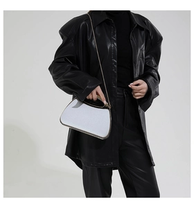 Detail of white sequined shell clutch bag with gold handle and chain on black outfit