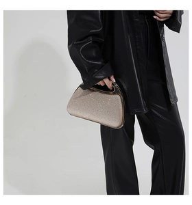 Close-up of champagne gold glitter evening bag with modern semi-circle metal handle