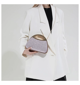 Detail of lavender glitter shell clutch with golden handle and chain on white suit