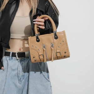 Borsa tote moto color cammello con borchie e manici intrecciati indossata da modella