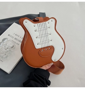 Close-up of guitar-shaped crossbody bag with silver studs and wide woven shoulder strap