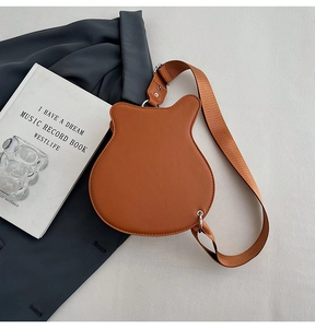 Detailed top view of brown guitar shaped crossbody bag with vintage stud hardware and strap