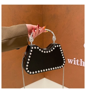 Detail of a black studded handbag featuring silver rivets and a sleek metal handle