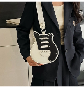 Detail of guitar-shaped crossbody bag with rivet accents and wide fabric shoulder strap