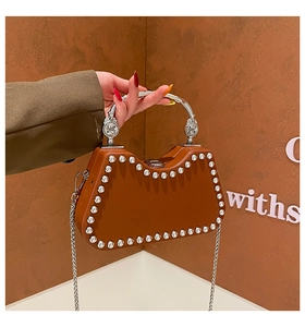 Detail of brown geometric tote with silver studs and metal handle on a brown wall
