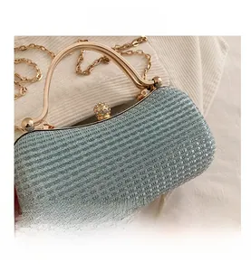 Close-up of glittery box clutch with gold metal handle and rhinestone ball clasp