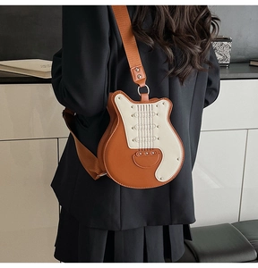 Detail of guitar-shaped crossbody bag with rivets and brown nylon strap on a model