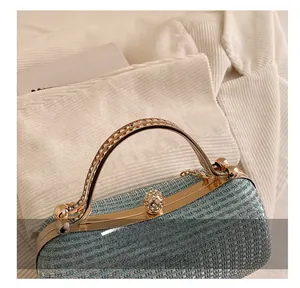 Close-up of light blue glitter clutch bag with rhinestone handle and gold metal clasp detail