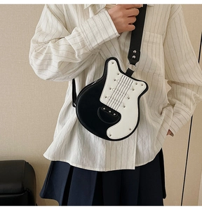 Close-up of guitar-shaped crossbody bag with white detailing and wide strap