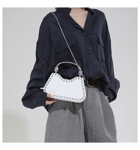 Detail of white fashion box bag with silver studs and metal handle shown with model