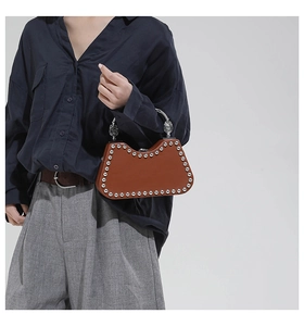 Détail du sac marron à rivets argentés avec poignée métallique gravée vintage