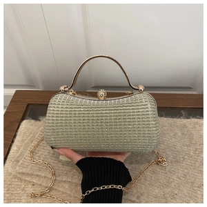 Detail of champagne gold evening clutch with rhinestones, metal handle and sphere lock