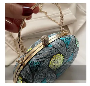 Detalle de bolso de fiesta con lentejuelas, asa dorada y cierre de bola con strass