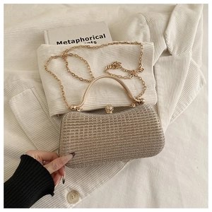 Detail of gold textured evening box bag with rhinestone sphere clasp and metal handle