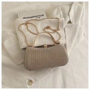 Detail of champagne evening bag featuring sparkling crystal clasp and metallic texture
