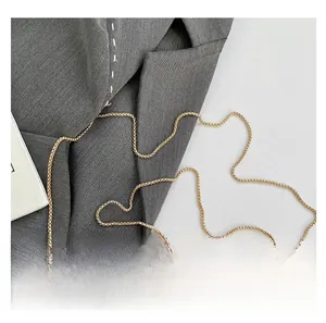 Detail von goldenem Metallgriff und gewebter Kette an Strohtasche mit Business-Outfit