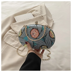 Detalle de bolso de fiesta con bordado de hojas y lentejuelas con asa dorada