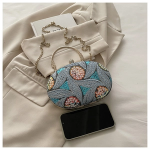 Detalle de bordado floral con lentejuelas y asa de metal retro en bolso de gala oval