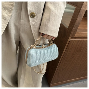 Close-up of light blue evening box bag featuring rhinestone handle and golden chain strap
