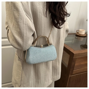 Detail of light blue textured evening bag with gold handle and pearl clasp on a model