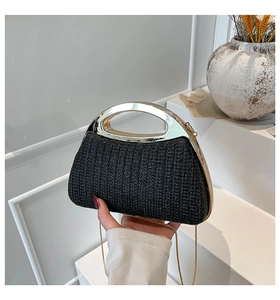 Détail d'un sac à main en paille tressée noire avec anse en métal et chaîne dorée