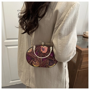 Detalle de un bolso de noche vintage burdeos con bordado floral y asa metálica