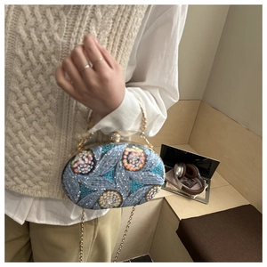 Detalle de bolso de fiesta con lentejuelas y cuentas con asa de metal dorado y cadena