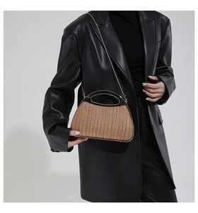 Detail der Stroh-Handtasche mit goldenem Hohlgriff und metallischem Kettenriemen