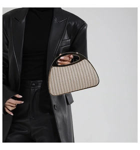Detail einer handgewebten Muscheltasche mit goldenem Metallgriff, präsentiert am Modell