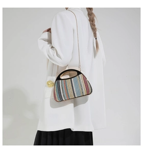 Détail du sac tressé multicolore avec poignée noire et élégante bandoulière en chaîne dorée