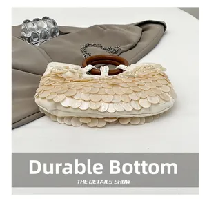 Detail der Pailletten-Muscheltasche mit runden Holzgriffen und abriebfestem Boden